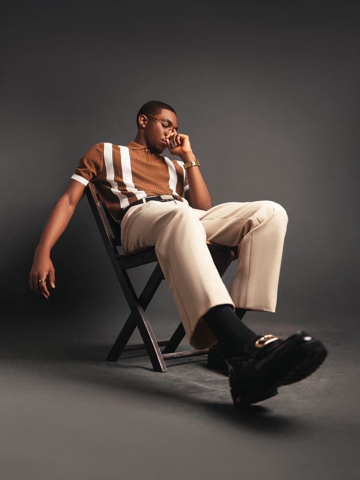 Editorial portrait of a man seated against a grey studio backdrop